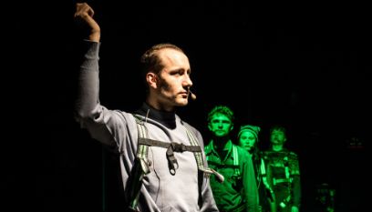 Bühnensituation, Schauspieler*innen hintereinander aufgereiht in grünem Licht