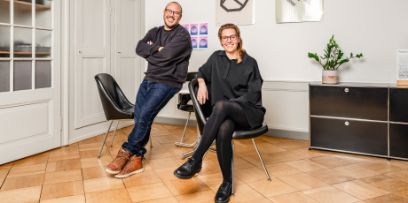 Ein Mann und eine Frau schauen in die Kamera. Dabei handelt es sich um Sébastian Fasel und Fabienne Kilchör von Emphase GmbH.