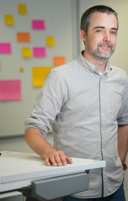 Ein Mann steht vor einem Whiteboard mit farbigen Post-it-Zetteln