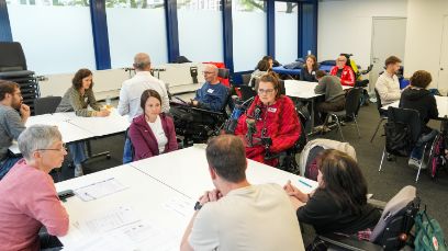 People with and without physical disabilities were sitting together at tables in a seminar room.