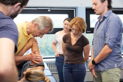 Ein Dozent der Physiotherapie zeigt Student*innen eine Behandlungsmethode