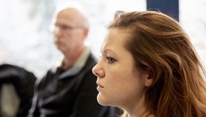 Zwei ernstblickende Personen, Frau im Vordergrund im Profil, Mann unscharf im Hintergrund