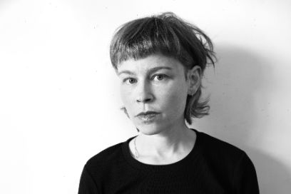 Portrait von Julian Koechlin. Er ist mittig abgebildet und blickt nachdenklich in die Kamera, Schlagschatten im Gesicht. 