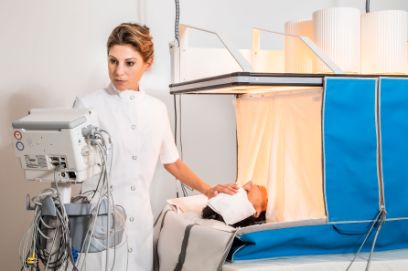 Gesundheitsfachperson bedient Heckel-Bett und legt kühles Tuch auf die Stirn der Patientin