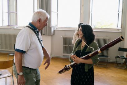 Ein älterer Herr und eine junge Frau mit Musikinstrument unterhalten sich