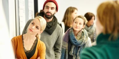 Vier Personen sitzen in einem Seminarraum und hören zu.