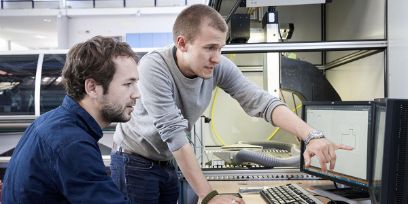 Illustrationsbild: Laborsituation mit zwei Männern vor dem Computermonitor, den Inhalt besprechend.